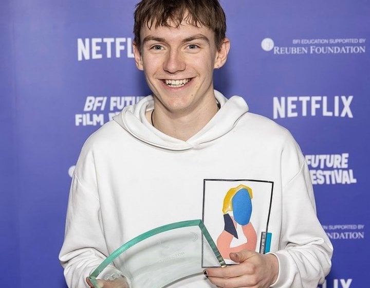 Will Wightman - dressed in a white hoodie - poses with his Best Director Award